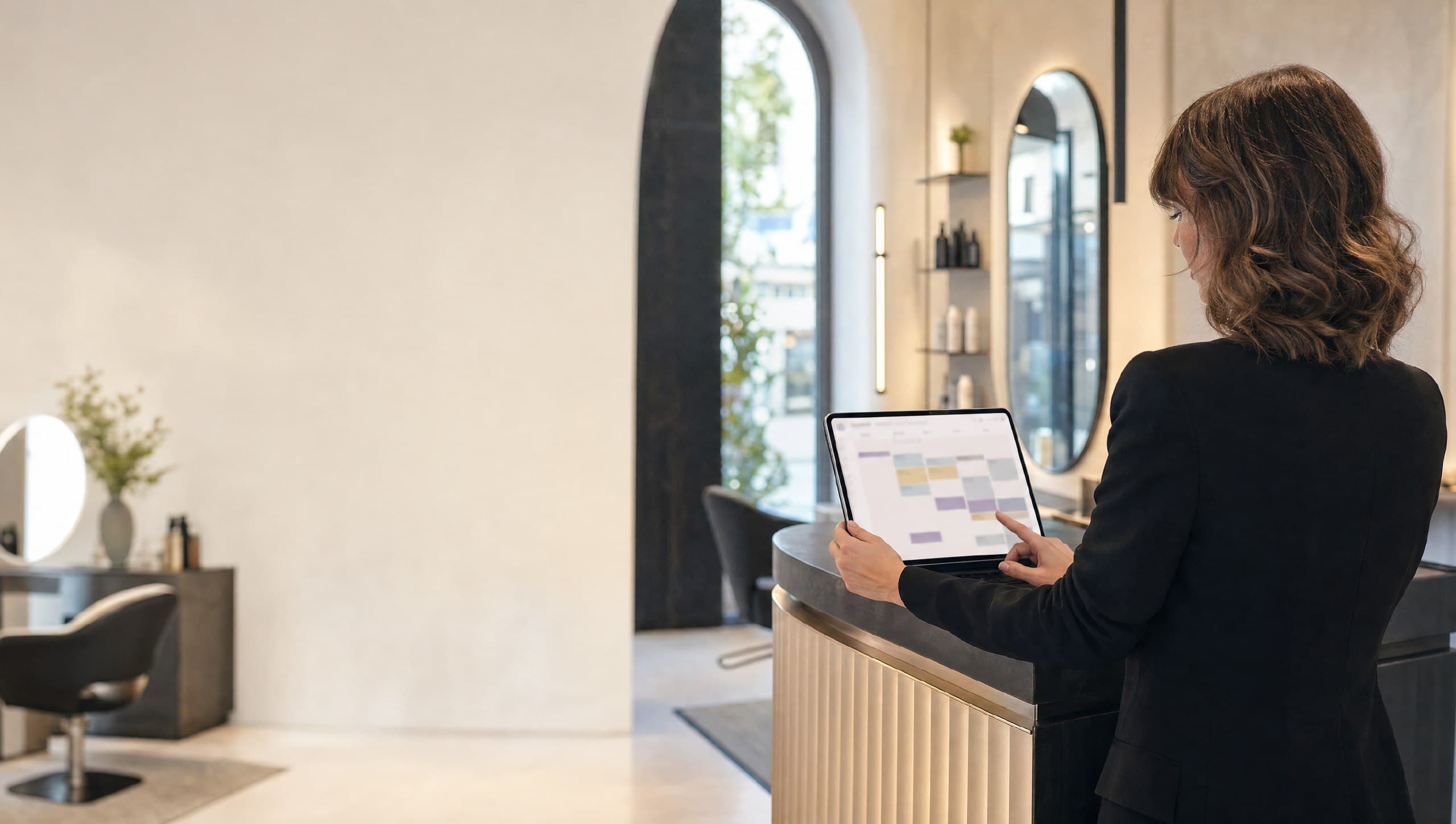 Titolare di un salone gestisce gli appuntamenti del giorno su tablet al banco reception